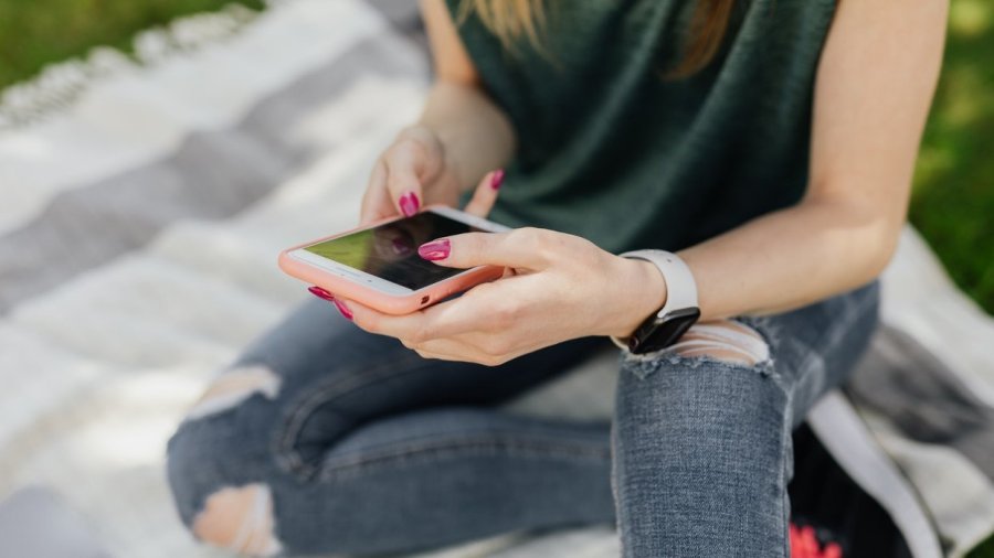 Chica joven consultando el teléfono móvil.